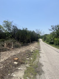 a dirt road next to a wooded area